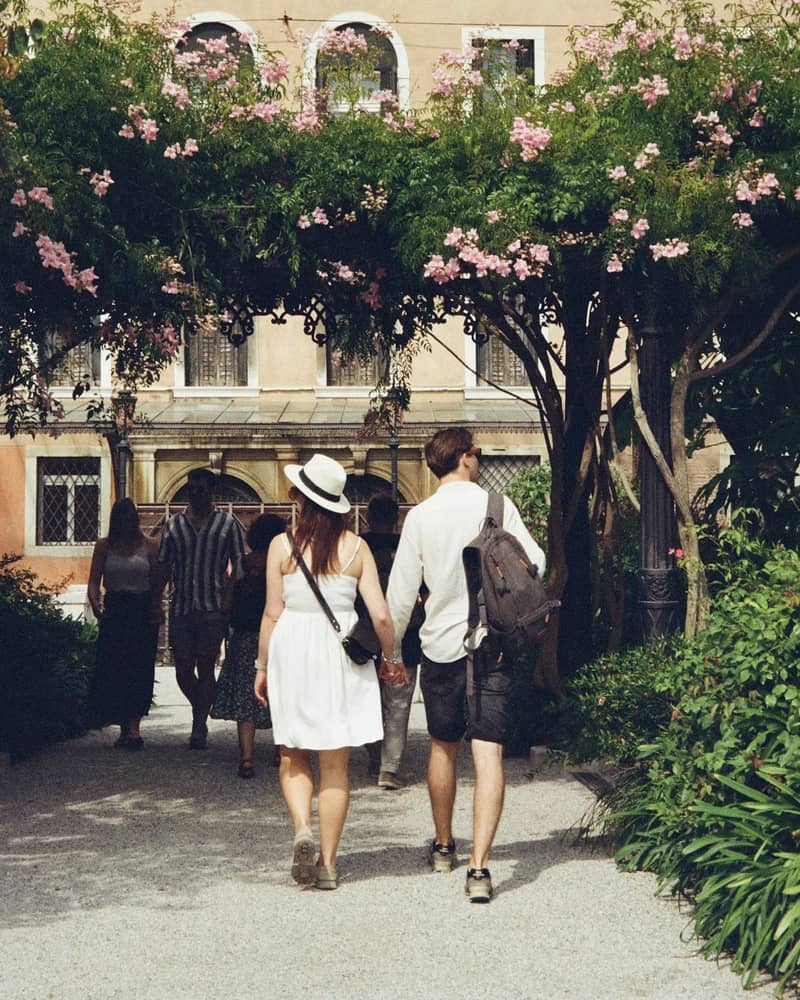 The couple walking hand in hand under a flowering archway