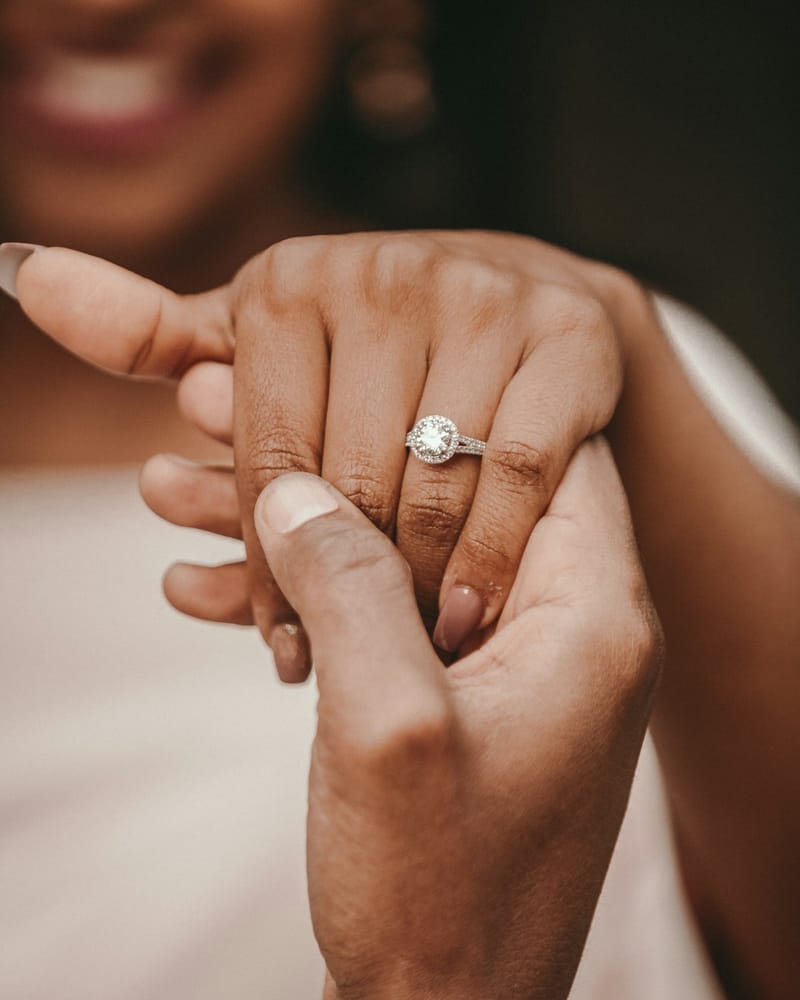 Holding hands, showing off a diamond engagement ring